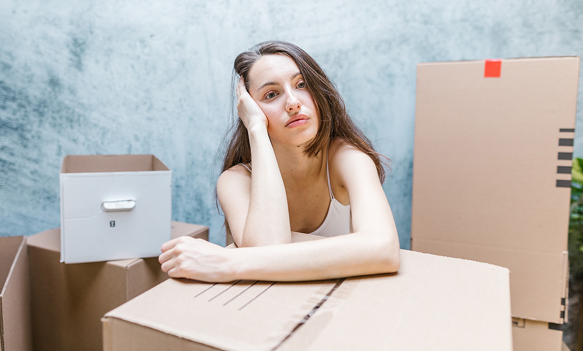 Femme triste parmi des cartons dans un appartement