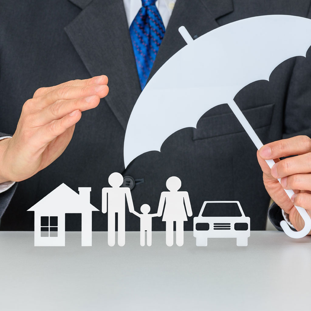 Main d’un professionnel en costume tenant un parapluie au-dessus de silhouettes d’une maison, d’une famille et d’une voiture, symbolisant la protection du patrimoine grâce aux mesures conservatoires.